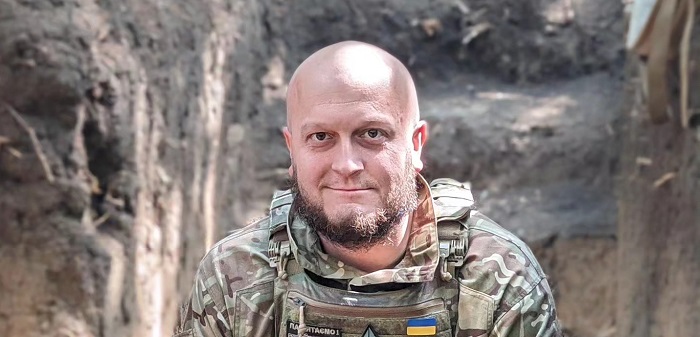 Тарас Давидюк сидить у військовій формі у бронежилеті в окопі