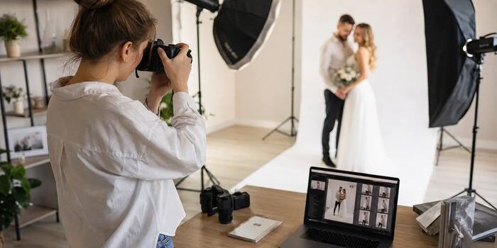 Жінка-фотограф у сучасній фотостудії фотографує пару